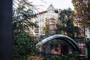 curved, metal pipeline, walkway railing, urban, river, surrounded, buildings, trees, construction, equipment, flowing
