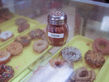 cocoa, glass shaker, sitting, counter, donut shop, shop., glass, food, dispenser, container, sweet