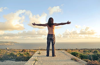 man, wearing, denim jeans, standing, seashore, arms stertched, adult, back, green, horizon, land