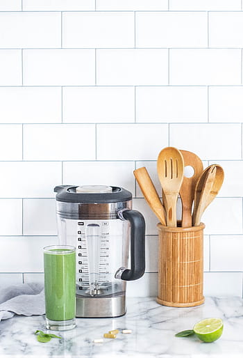 green smoothie, vegetable juice, healthy drink, fruit smoothie, lime juice, blender, kitchen countertop, wooden utensils, marble countertop, white subway tiles, green beverage